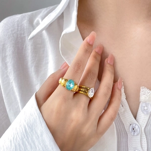 Macro shot of gold-plated rings with blue oval gemstone and pear-cut zircon detail