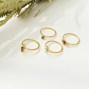 Detail of four 18K gold plated minimalist rings with red, purple and clear stones