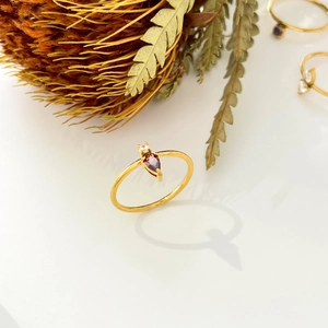 Detail of 18K gold ring featuring a teardrop red zircon and small round stone