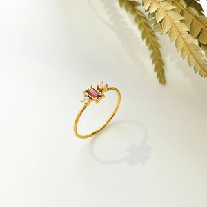 Macro detail of 18K gold-plated ring with rectangular red stone and side zircons