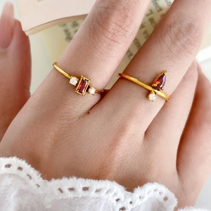 Detailed close-up of 18K gold plated rings with red rectangular and pear-shaped gemstones