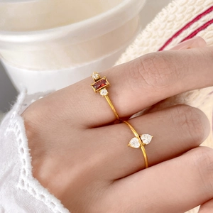 Detail of 18K gold plated rings featuring rectangular ruby and teardrop cubic zirconia