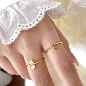 Detail of 18K gold plated titanium rings with heart zirconia and purple square gemstone