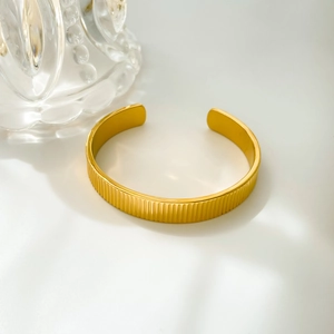 Close-up of golden titanium steel cuff bracelet with vertical striped texture details