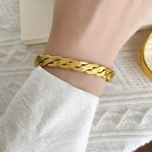 Close-up of thick gold-plated titanium steel twisted cuff bracelet on a female wrist