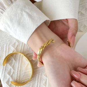 Chic gold-toned crisscross woven cuff bracelet with triple-layered curved titanium steel band