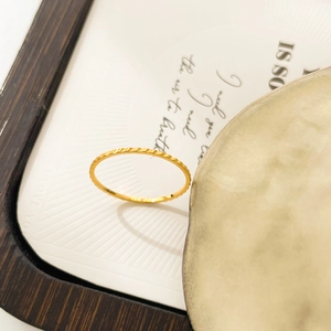 Detail shot of golden wave texture ring on decorative stone and wooden tray background