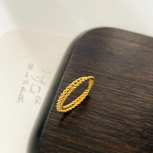 Macro shot of 18K gold plated twisted rope ring showing detailed woven texture on wood