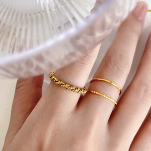 Detail of 18K gold plated stackable titanium steel rings with twisted and hammered textures