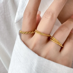 Macro shot of three textured gold-plated titanium steel rings worn by a model