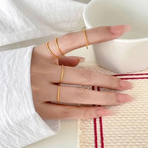 Close-up of stacked 18K gold plated titanium steel rings with twisted texture detail