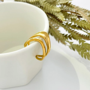 Golden double-layer geometric ring hanging on a white ceramic cup with dried plants