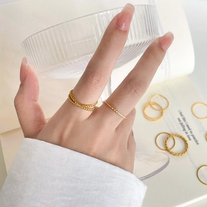 Close-up of stacked gold twist and textured titanium rings worn by a model