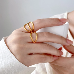 Close-up of geometric 18K gold plated titanium double ring with hollow intertwined lines
