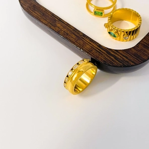 Detailed view of 18K gold plated titanium rings with green zircon and gear textures
