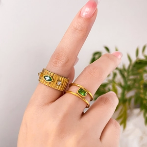 Detail of 18K gold plated titanium rings with green zircon and vintage textured finish