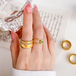 Detailed view of layered 18K gold rings featuring green zircon and sparkling diamond accents