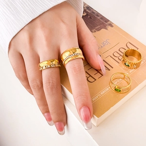 Detail of 18K gold plated titanium steel rings with green zircon on a minimalist background