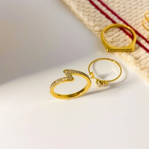 Primo piano dell'anello a fulmine dorato e anelli in titanio con zirconi incastonati