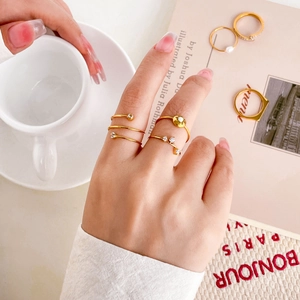 Dettaglio di anelli placcati in oro con perle, zirconi e design minimalisti a spirale