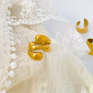 Macro detail of high-polish irregular 18K gold plated spiral ring on white lace cloth