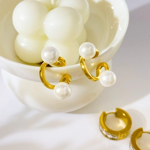 Détails de boucles d'oreilles perles et anneaux zircon plaqués or 18 carats sur un bol
