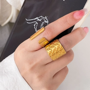 Detail of wide hammered texture and minimalist double-line gold rings on model