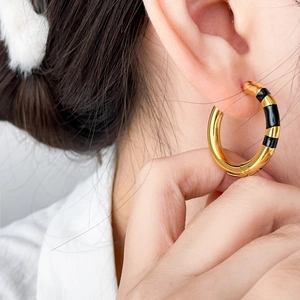 Créoles modernes en titane plaqué or 18 carats avec rayures en émail noir sur modèle