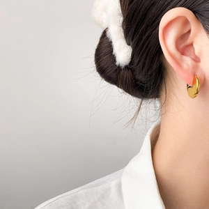 Vue détaillée de boucles d'oreilles dorées ondulées en titane plaqué or 18 carats