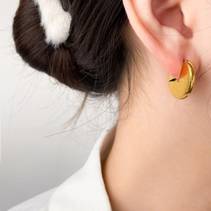 Gros plan sur une boucle d'oreille minimaliste en acier plaqué or 18 carats sur un mannequin