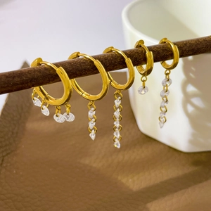 18K gold plated titanium tassel earrings with zirconia crystals on a wooden stand
