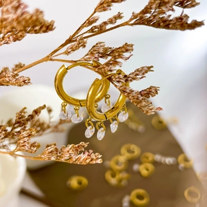 Detail of 18K gold-plated hoop earrings with five marquise-cut zircon charms on dried branch
