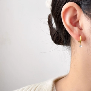 Detail shot of a long 18K gold-plated tassel earring with zircon stone on model's ear