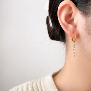 Detail of dangling tassel earrings in 18K gold plated steel with sparkling zircon stones