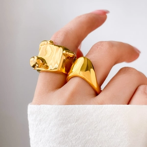 Détail d'une bague dôme dorée minimaliste et d'une bague à texture irrégulière au doigt