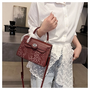 Close-up of burgundy Kelly bag featuring lattice texture and white lace ribbon detail