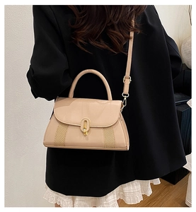 Détail du sac beige montrant la texture tressée latérale et le fermoir doré ovale