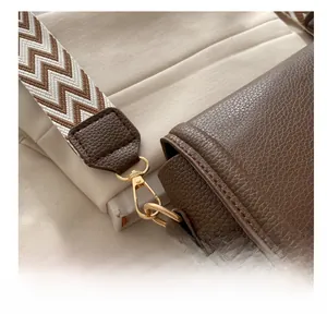 Detailansicht der dunkelbraunen Lederhandtasche mit Goldhaken und gewebtem Tragegurt
