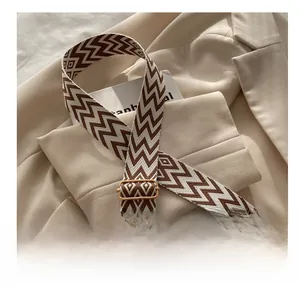 Detail eines gewebten Schultergurts mit goldener Metallschnalle auf einem Blazer-Hintergrund