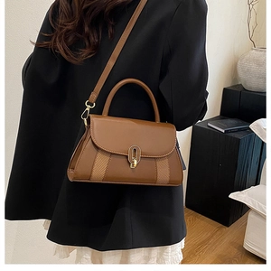 Détail d'un sac bandoulière en cuir marron avec fermoir rotatif doré et panneaux texturés