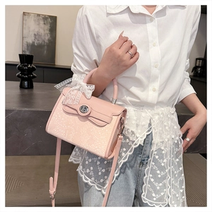 Detail of pink kelly bag featuring snake embossed texture and white lace bow decoration