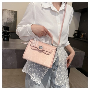 Pink embossed handbag detail with lace bow and silver twist lock on model outfit