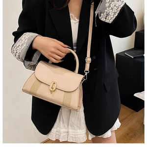 Détail du sac beige avec rayures tissées et fermoir rotatif doré élégant pour femme