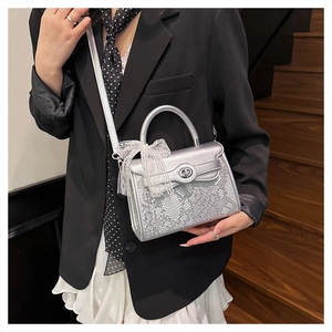 Detailed view of silver snakeskin texture handbag with lace bow and metal clasp