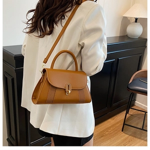 Détail du sac bandoulière camel avec fermoir doré et texture tressée sur modèle