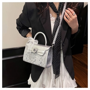 Silver snakeskin embossed handbag featuring a white lace bow and silver hardware lock detail