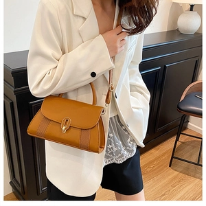 Détail d'un sac bandoulière marron avec boucle dorée et textures tissées latérales