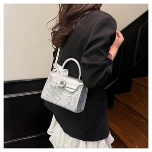 Silver snakeskin embossed handbag featuring a white lace bow detail and metal lock closure