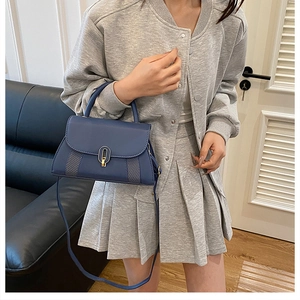 Sac bandoulière bleu marine avec fermoir doré et motif matelassé sur un mannequin