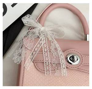 Detailed macro view of pink crocodile textured leather bag with silver twist-lock and lace bow